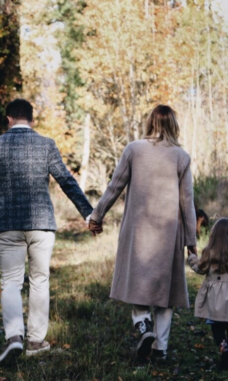 Familie Brunner mit den Kindern an der Hand, bei einem Spaziergang auf dem Feldweg von hinten Fotografiert.