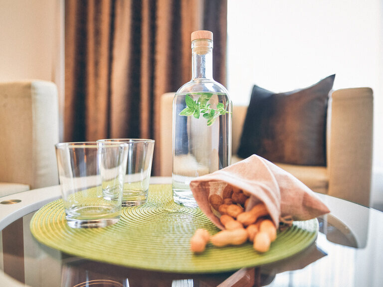 Nahaufnahme von Tisch der Sitzecke, mit Gläsern und Wasserflasche im Doppelzimmer Lusen im Hotel Eibl-Brunner.