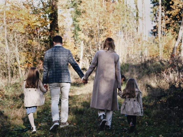 Familie Brunner mit den Kindern an der Hand, bei einem Spaziergang auf dem Feldweg von hinten Fotografiert.