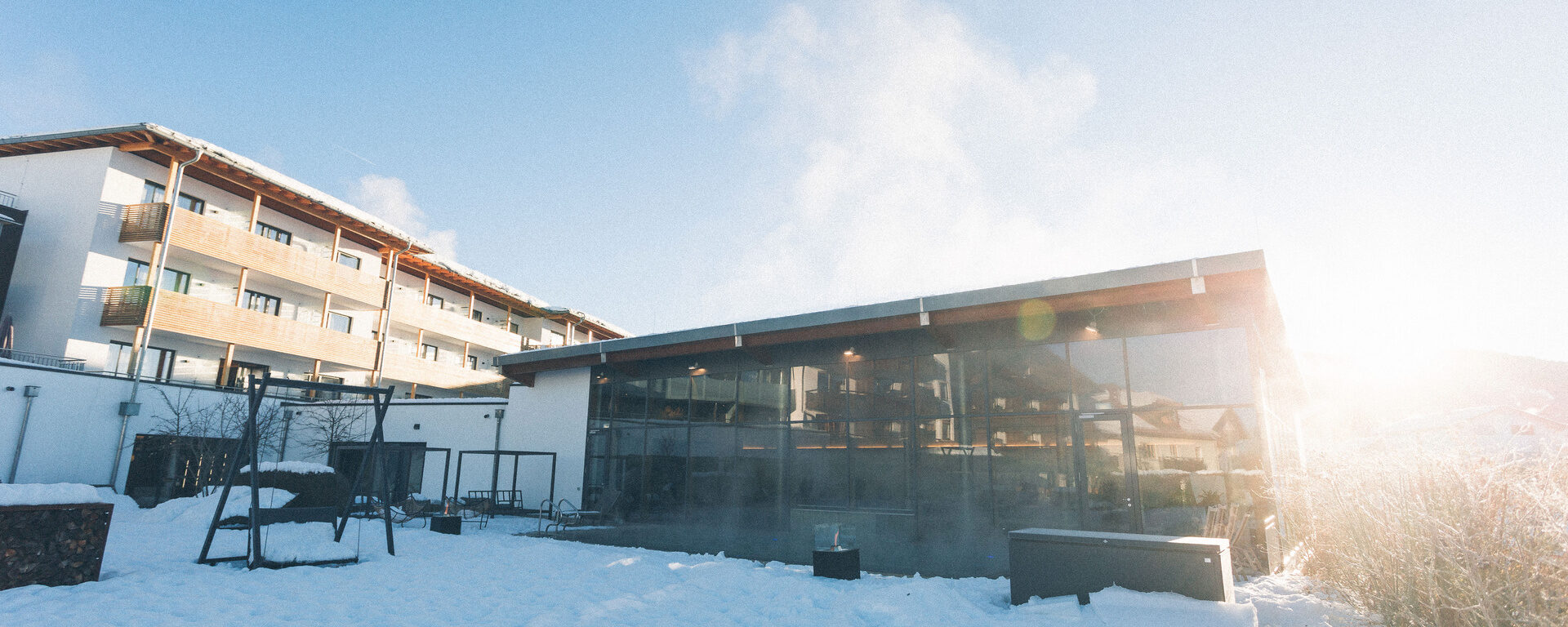 Hotel Gebäude Eibl-Brunner im Winter von der Sonne angestrahlt, dampfender Außenpool