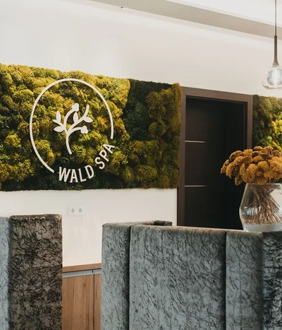 Eibl Brunner: dein Hotel in Frauenau Rezeption im Wald Spa mit Mooswand und Blumenstrauß in Vase