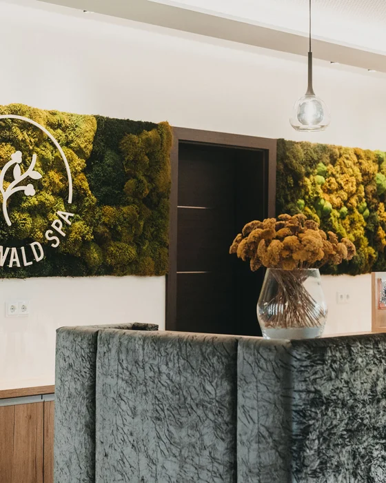 Eibl Brunner: dein Hotel in Frauenau Rezeption im Wald Spa mit Mooswand und Blumenstrauß in Vase