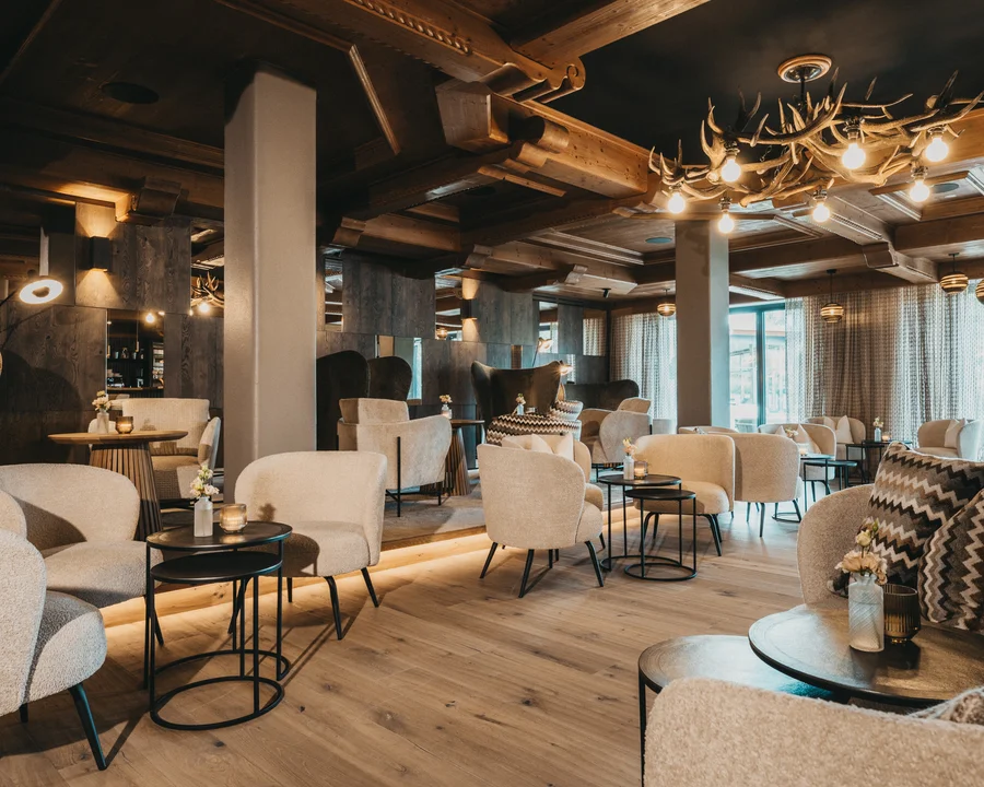 Eibl Brunner: dein Hotel in Frauenau Gemütliche Lounge mit beigen Sesseln, Holzboden und Hirschgeweih-Lampe