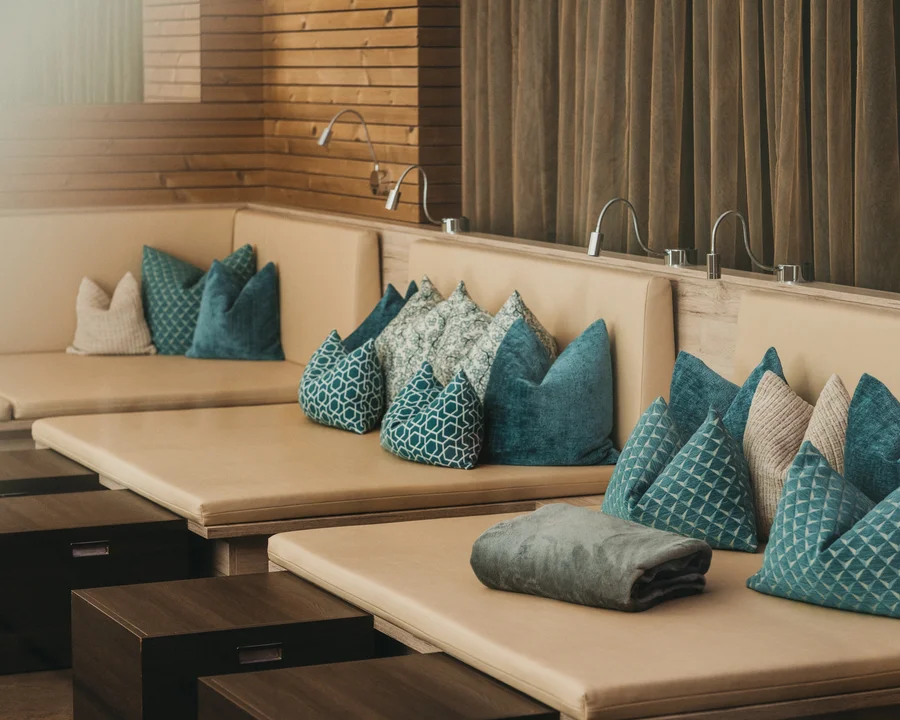 Eibl Brunner: dein Hotel in Frauenau Beige Lounge mit blauen und gemusterten Kissen und kleinen Holztischen